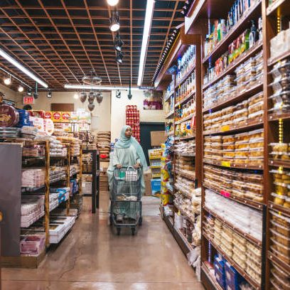 Black woman wearing abaya in a grocery store in New York, she walks thought production aisle